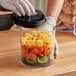 A hand using a Prepara Evak Fresh Saver container to store strawberries.