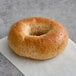 A Just Bagels wheat bagel with a hole in the middle on a white surface.