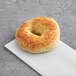 A Just Bagels Asiago bagel with a hole in the middle on a napkin.