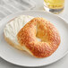 A Just Bagels asiago bagel with cream cheese on a white plate.