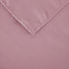 A folded pink rectangular Intedge table cover with a hemmed edge.