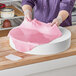 A person in purple gloves using a Baker's Lane foam round cake dummy to make a pink cake.