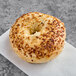 A Just Bagels onion bagel with sesame seeds on top.