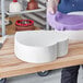 A white heart shaped cake dummy on a wooden surface.