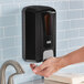 A person using a black and grey Lavex manual foaming soap dispenser.