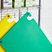 A shelf with green and yellow Choice cutting boards.