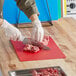 A person using a Choice multi-colored flexible cutting board to cut meat.