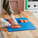 A person cutting salmon on a multi-colored flexible cutting board on a counter.