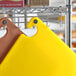 A yellow Choice cutting board on a metal rack.