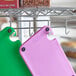 A purple plastic cutting board with grips and rulers on a metal rack.