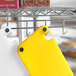 A yellow Choice cutting board on a metal rack with a hook.