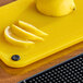 A yellow Choice cutting board with a lemon slice on it.