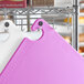 A purple Choice cutting board with grips and rulers on a metal rack.