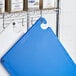 A blue Choice cutting board on a metal rack with spices.