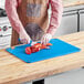 A man cutting lobster on a blue Choice cutting board with rulers.