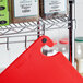 A red Choice cutting board on a metal rack.