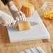 A person in gloves cutting a pumpkin on a white polyethylene cutting board.