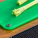 A green Choice cutting board with celery on it.