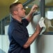 A person using a white paper wiper to clean an office partition window.