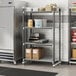 A Cambro Camshelving Elements metal shelving unit with food containers and boxes on the shelves.