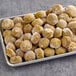 A tray of Kronos fully cooked falafel balls on a table.
