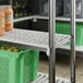 A Cambro Elements Camshelving® shelf with green baskets and containers of food.