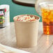 A Choice kraft paper food cup filled with food on a table.