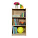 A Flash Furniture wood classroom storage cabinet with books and toys on top.