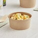 A bowl of macaroni and cheese in a Kraft paper food cup.