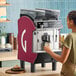 A woman using a Gaggia Concetto Evo Duo espresso machine to pour a coffee.