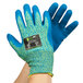 A pair of small blue and yellow Cordova iON A4 cut-resistant gloves with blue crinkle latex palms on a pair of hands.