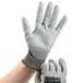 A person wearing gray and white Cordova Monarch cut-resistant gloves with gray palms.