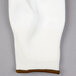 A pair of white knit gloves with brown trim on the wrist.
