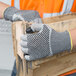 A person wearing Cordova Monarch cut-resistant gloves with nitrile dots holding a piece of wood.