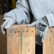 A person wearing Cordova Monarch gray cut-resistant gloves holding a piece of wood.