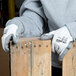 A person wearing Cordova white HPPE gloves holding a piece of wood.