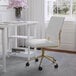 A Martha Stewart white faux leather armless office chair with a polished brass base.