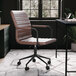 A Martha Stewart saddle brown faux leather swivel office chair with oil-rubbed bronze finish at a brown desk with a computer keyboard.