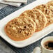 Pre-formed Michael's vegan chocolate chip walnut cookies on a plate with a cup of coffee.
