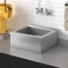 A Steelton stainless steel mop sink in a room with a mop and bucket.