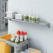 A Lavex stainless steel wall mount shelf with cleaning supplies and towels.