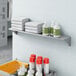 A Lavex stainless steel wall mount shelf with towels and bottles on it.