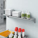 A Lavex stainless steel wall mount shelf with towels and bottles on it.