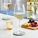 Two Acopa Select Flora wine glasses filled with white wine on a table