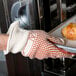 A hand wearing a Cordova hot mill glove holding a tray of bread.