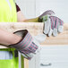 A person wearing Cordova striped canvas work gloves with leather palm coating and rubber cuffs holding a piece of wood.