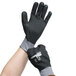 A person wearing gray Cordova warehouse gloves with black full coating and nitrile dots on the palm.