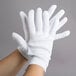 A pair of hands wearing white Cordova inspection gloves.