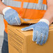 A person wearing Cordova work gloves holding a box.