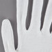 A close up of a Cordova white inspection glove with a black stripe on the wrist.